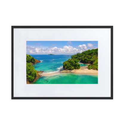 Aerial view of clear blue colored water at the edge of a white sand beach with jungle island plants