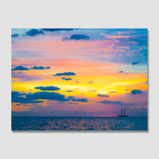 Distant schooner ship with colorful spectrum sky and cloud formations