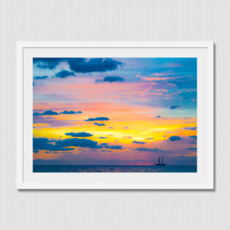 Distant schooner ship with colorful spectrum sky and cloud formations