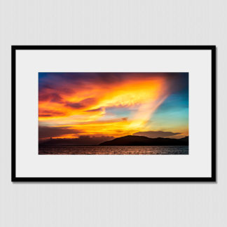 Bright orange and red color bursts through amazing cloud formations during a sunset over Pacific Panama.